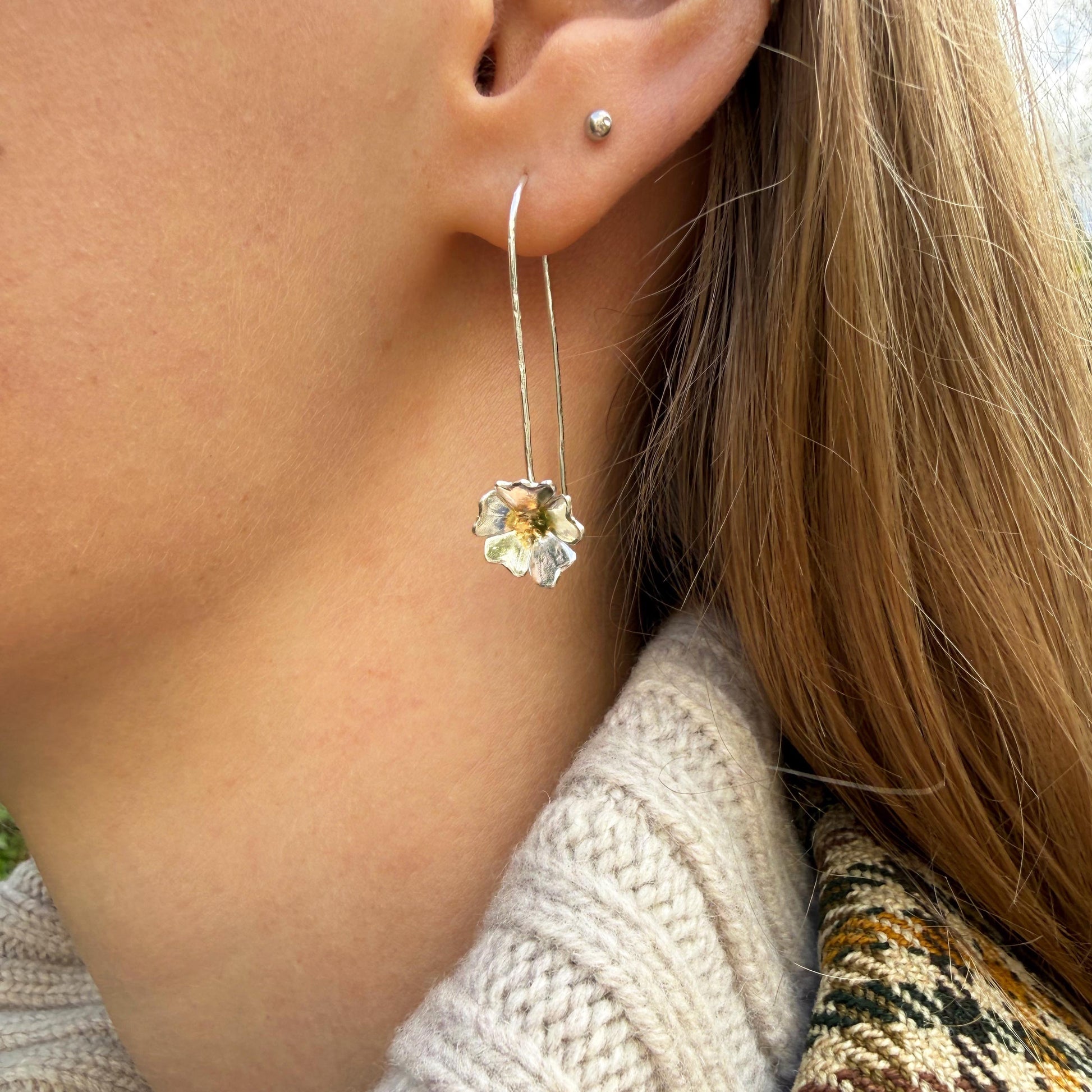 The Expanded Skies Dartmoor Field Rose Drop Earrings capture the joyous simple beauty of the field rose, Rosa arvensis, that is seen weaving brightly through the Dartmoor hedgerows and woodland. Hand pierced and formed in recycled fine silver with recycled 24ct gold accents and recycled sterling silver ear wires. 