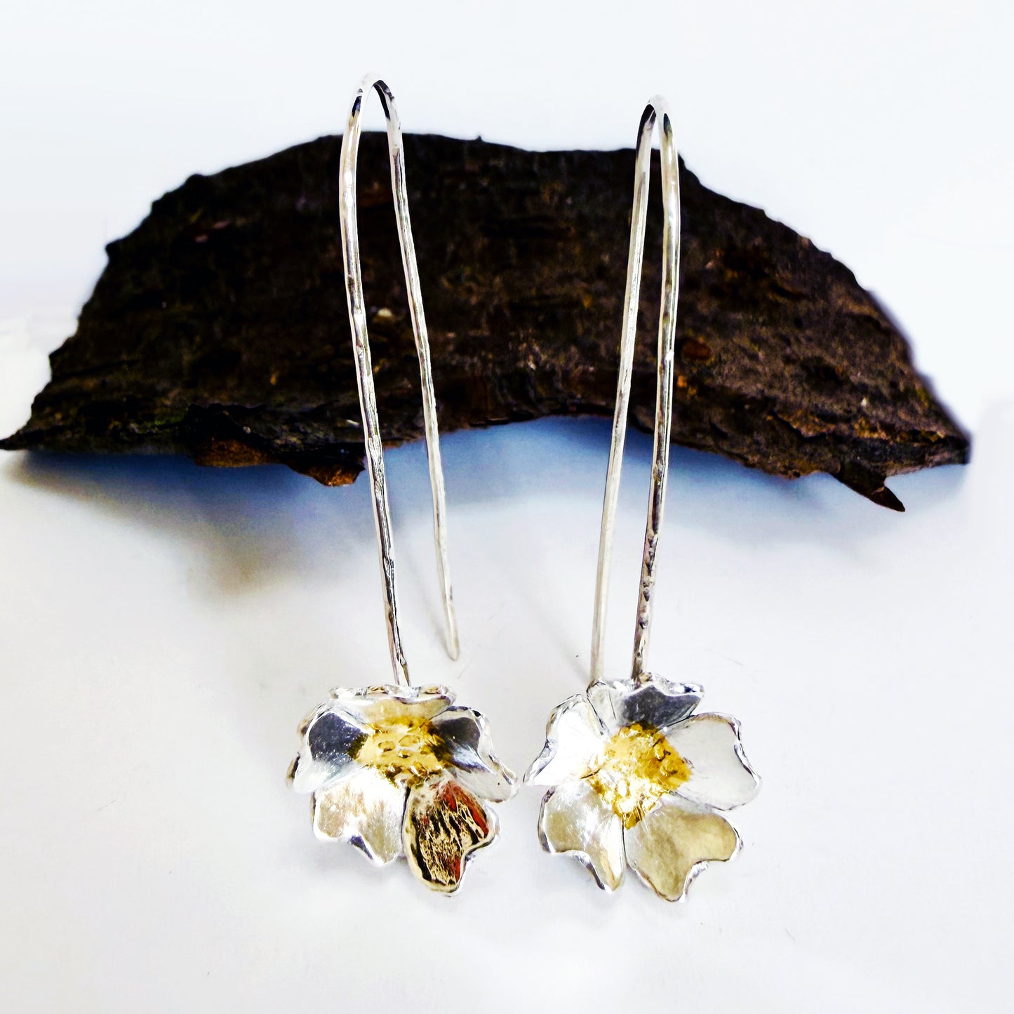 The Expanded Skies Dartmoor Field Rose Drop Earrings capture the joyous simple beauty of the field rose, Rosa arvensis, that is seen weaving brightly through the Dartmoor hedgerows and woodland. Hand pierced and formed in recycled fine silver with recycled 24ct gold accents and recycled sterling silver ear wires. 