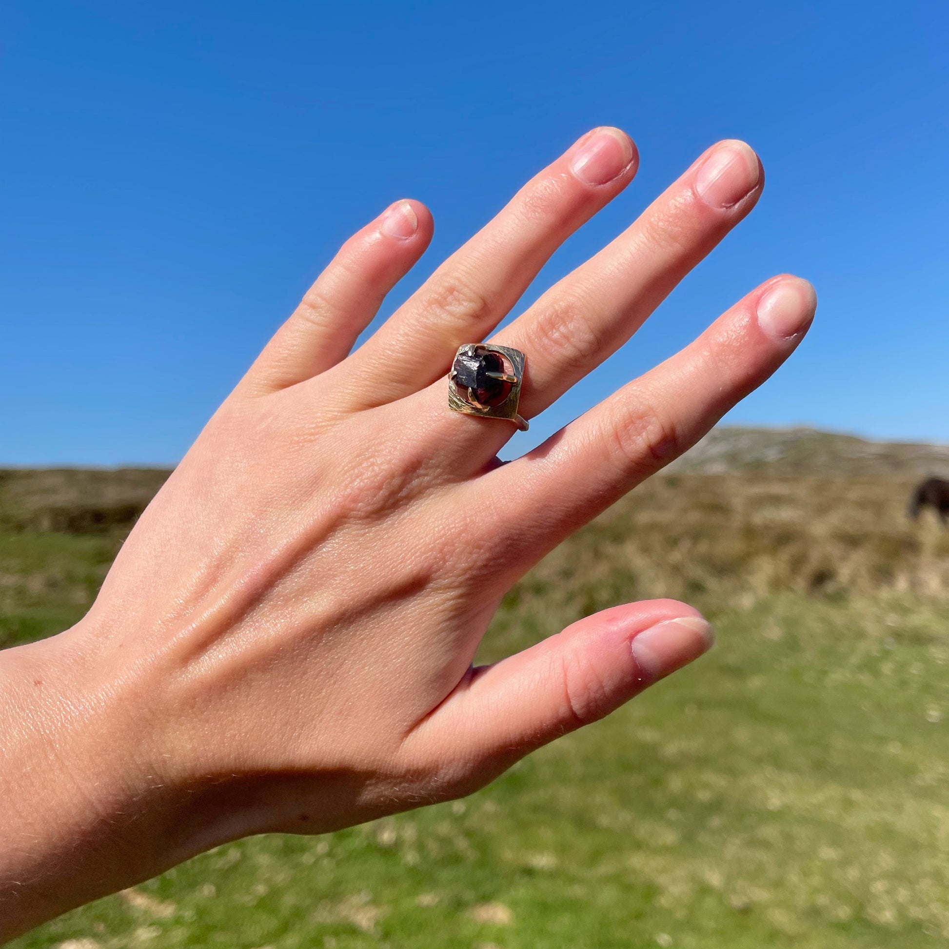 The Expanded Skies Heaven and Earth Raw Garnet Ring has a beautiful raw Norwegian garnet set in 9ct gold. The garnet is set in a distinctive completely handcrafted engraved claw setting. This is a unique piece, one-of-a-kind. Handcrafted on the edge of Dartmoor and made from high quality recycled gold, Hallmarked by the London Assay Office.