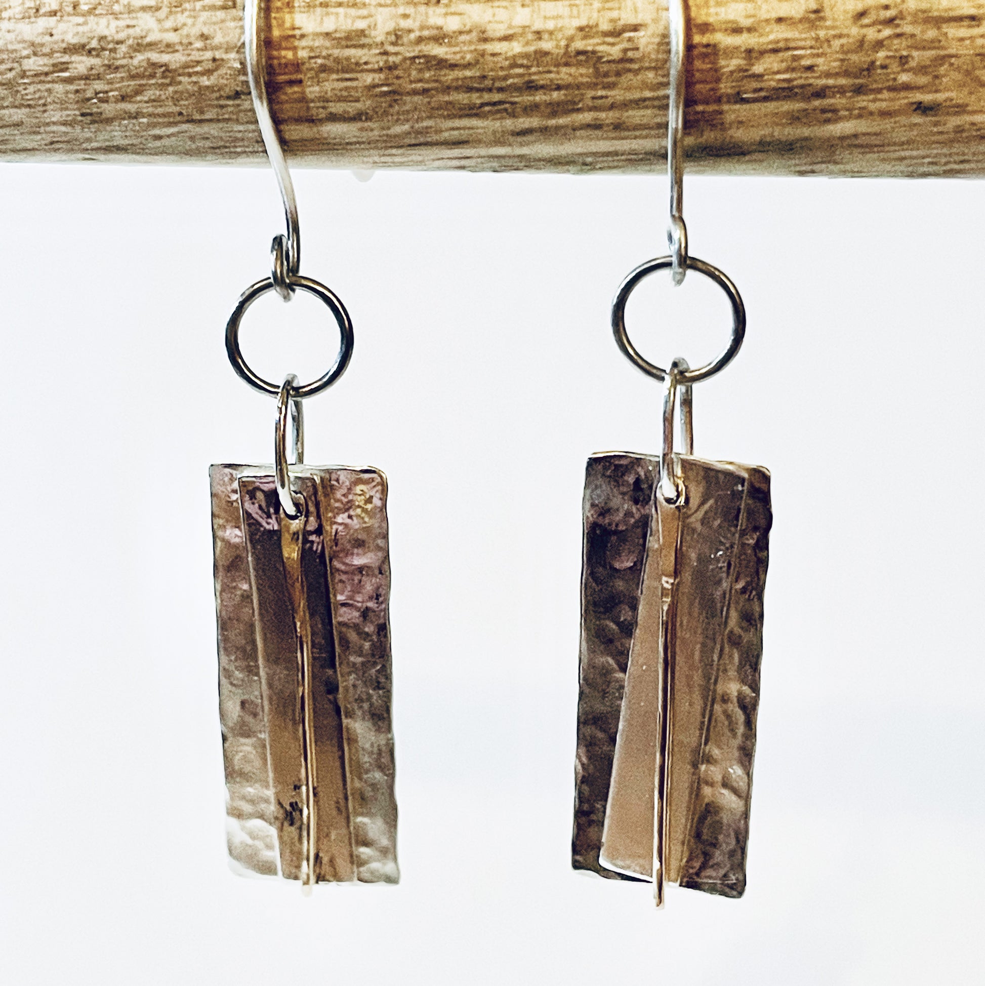 The Dartmoor Dart Valley earrings, are inspired by the River Dart, that viewed from high on top of granite moorland, glints and snakes through the steep sides of the deeply wooded valley.  Handcrafted layers of solid recycled sterling silver are hammered and polished with a fine 9ct gold bar, that swing and catch the light.