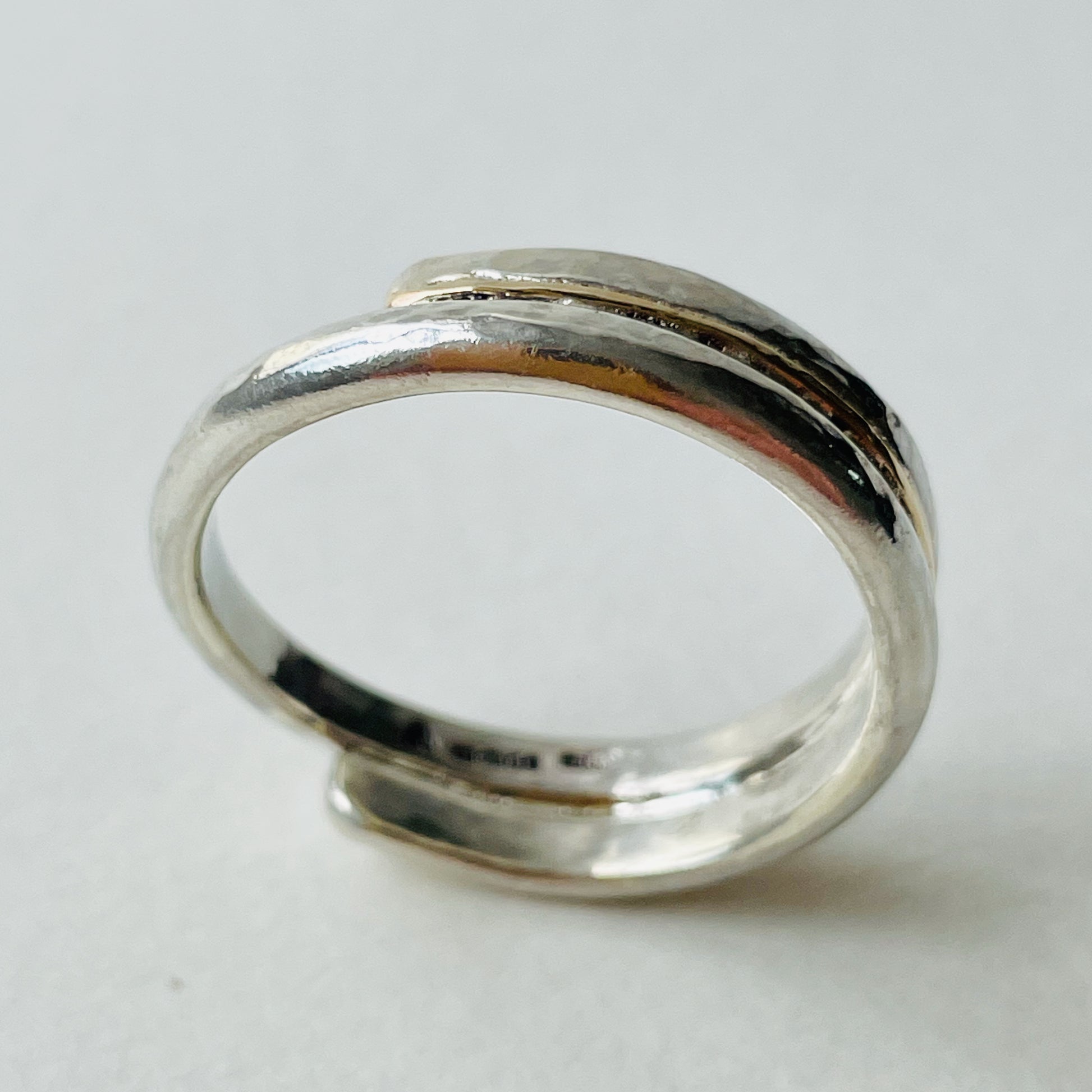 The Dartmoor Dart Valley Hammered Ring, inlaid with 9ct Gold, is inspired by the River Dart, that viewed from high on top of granite moorland, glints and snakes through the steep sides of the deeply wooded valley. The hammered band is handcrafted from a single band of sold sterling recycled silver at back that flows into a recycled 9ct gold band at the front, flanked by two silver bands. Wear everyday, perfect as a wedding ring or to accompany any outfit, understated, beautiful.