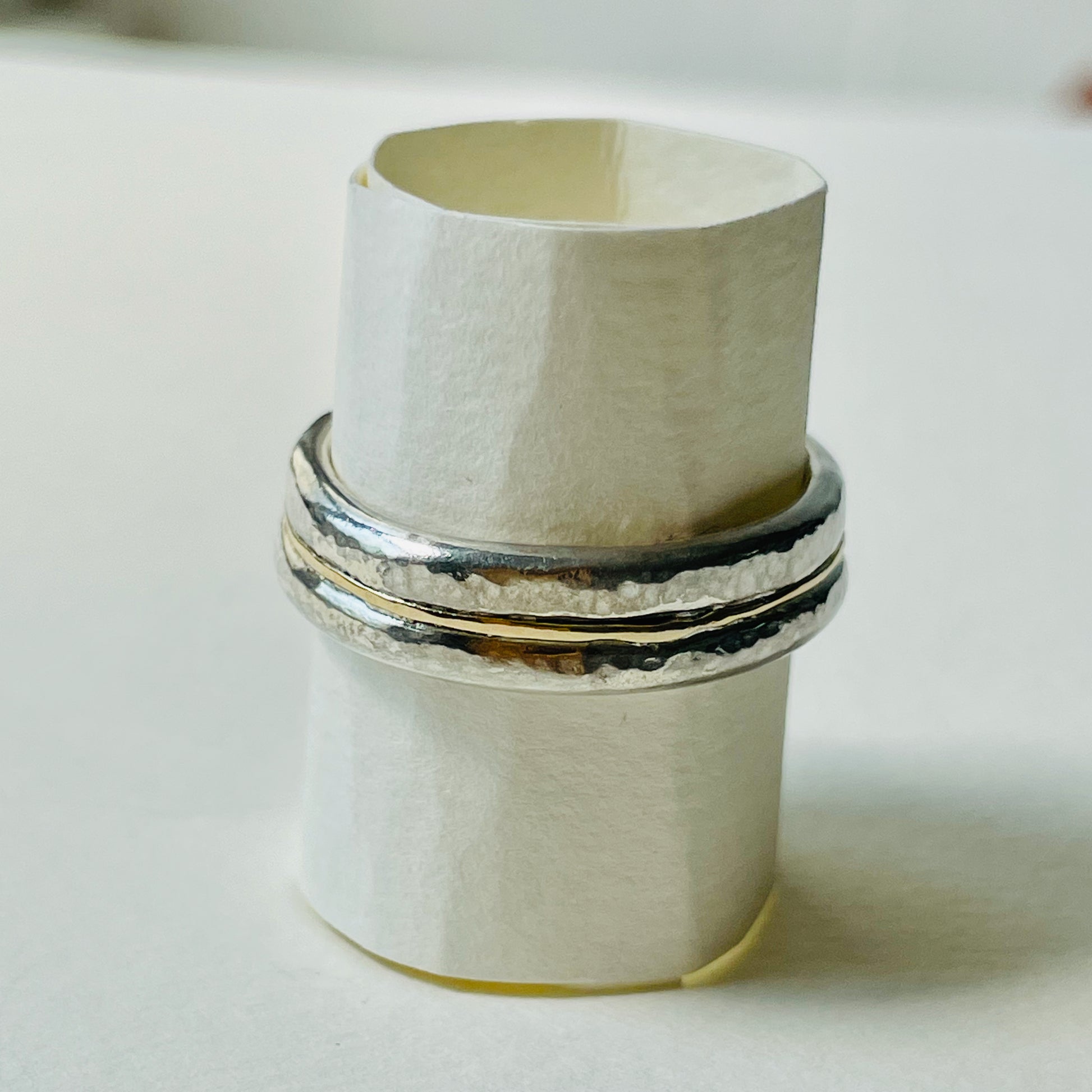 The Dartmoor Dart Valley Hammered Ring, inlaid with 9ct Gold, is inspired by the River Dart, that viewed from high on top of granite moorland, glints and snakes through the steep sides of the deeply wooded valley. The hammered band is handcrafted from a single band of sold sterling recycled silver at back that flows into a recycled 9ct gold band at the front, flanked by two silver bands. Wear everyday, perfect as a wedding ring or to accompany any outfit, understated, beautiful.