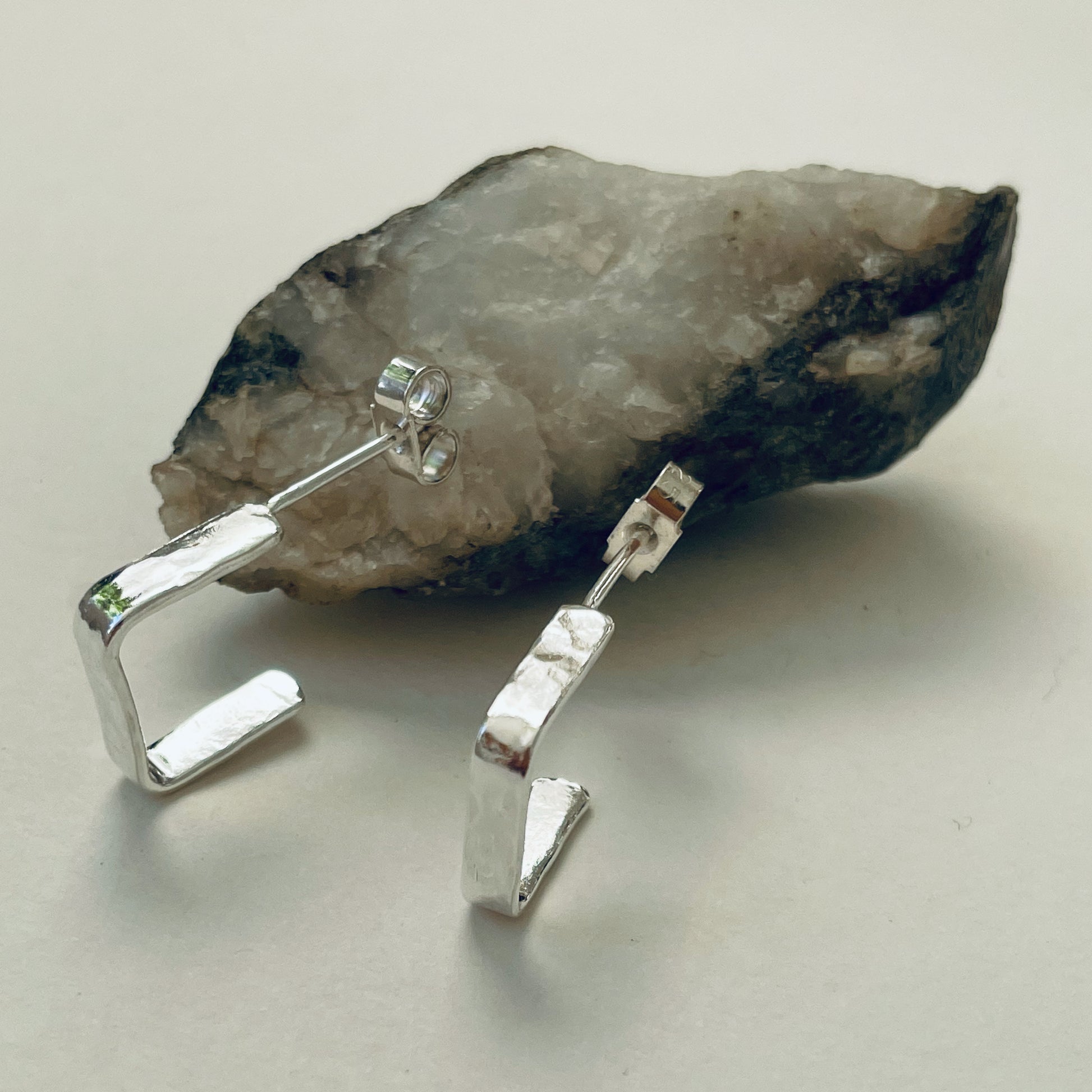 Evoking the angular boulders of Dartmoor, the Expanded Skies, Dartmoor Square Hoop Earrings are handcrafted from solid recycled sterling silver with a recycled sterling silver pin and scroll back. Simple and elegant, with a hammered finish they can be worn everyday for any occasion.