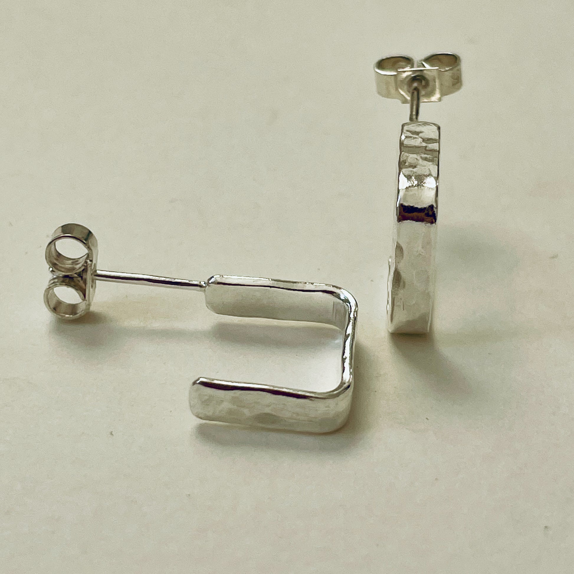 Evoking the angular boulders of Dartmoor, the Expanded Skies, Dartmoor Square Hoop Earrings are handcrafted from solid recycled sterling silver with a recycled sterling silver pin and scroll back. Simple and elegant, with a hammered finish they can be worn everyday for any occasion.