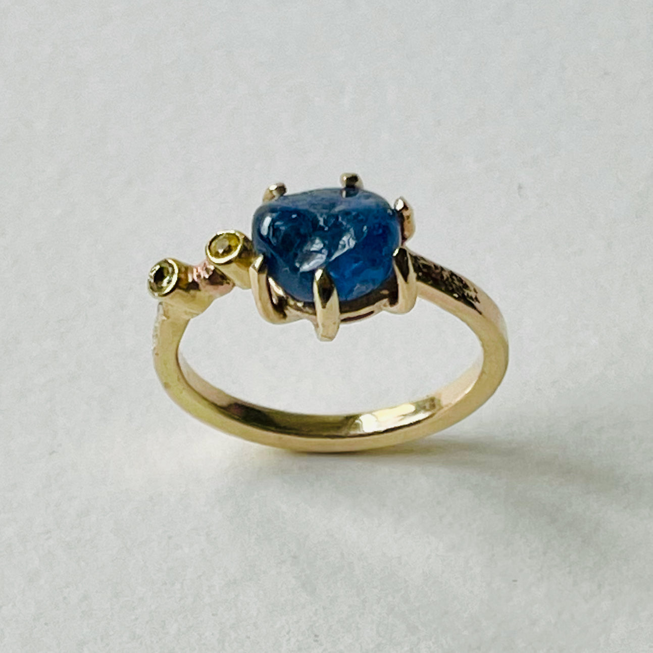 The Dartmoor Sun and Skies Sapphire Ring reflects the big Dartmoor skies, the contrasting colours and textures of the moving light over the landscape, created with ethically sourced raw and facetted sapphires and different shades of gold.