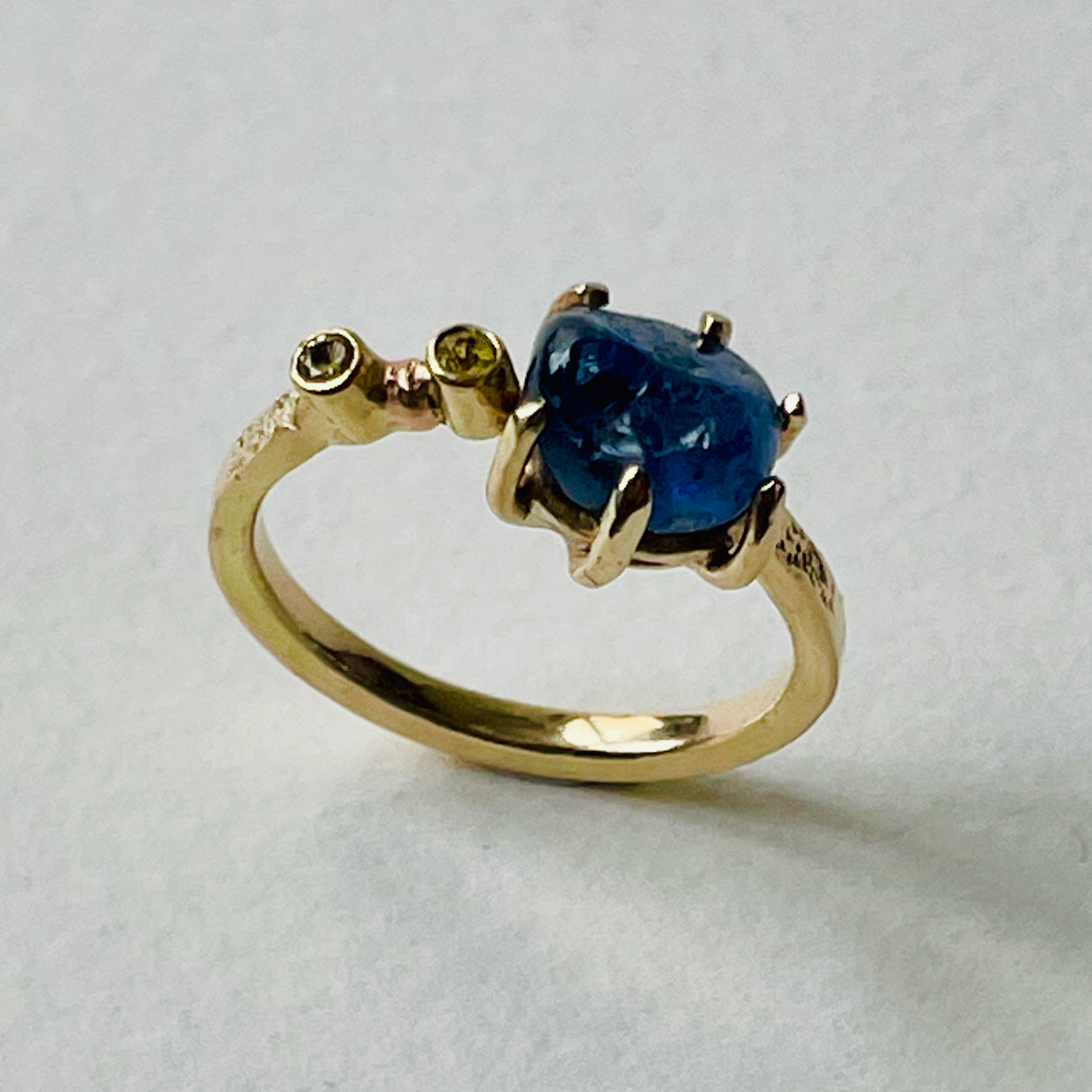 The Dartmoor Sun and Skies Sapphire Ring reflects the big Dartmoor skies, the contrasting colours and textures of the moving light over the landscape, created with ethically sourced raw and facetted sapphires and different shades of gold.