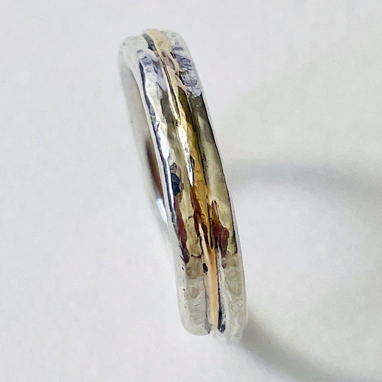 The Dartmoor Dart Valley Hammered Ring, inlaid with 9ct Gold, is inspired by the River Dart, that viewed from high on top of granite moorland, glints and snakes through the steep sides of the deeply wooded valley.  The hammered band is handcrafted from a single band of sold sterling recycled silver at back that flows into a recycled 9ct gold band at the front, flanked by two silver bands.  Wear everyday, perfect as a wedding ring or to accompany any outfit, understated, beautiful.