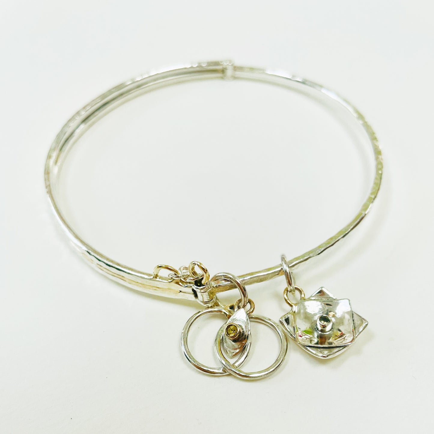 Expanded Skies Hinged Charm Bangle is made from high quality recycled sterling silver inlaid with recycled 9ct gold with a textured hammered finish that reflects the light. Understated and beautiful, it can be worn every day or for special occasions. The hinged bangle includes two charms set with beautiful ethically sourced Sri Lankan yellow sapphires, a star and a Vesica Piscis - two overlapping circles, used by many cultures, its meanings include harmony, balance and creation. Other charms can be added.