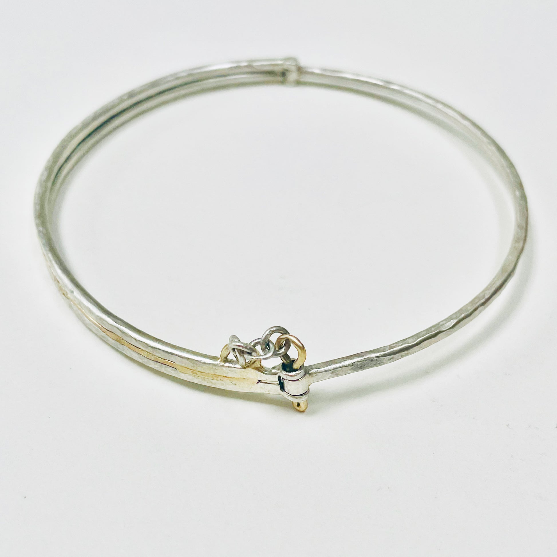 Expanded Skies Hinged Charm Bangle is made from high quality recycled sterling silver inlaid with recycled 9ct gold with a textured hammered finish that reflects the light. Understated and beautiful, it can be worn every day or for special occasions. The hinged bangle includes two charms set with beautiful ethically sourced Sri Lankan yellow sapphires, a star and a Vesica Piscis - two overlapping circles, used by many cultures, its meanings include harmony, balance and creation. Other charms can be added.