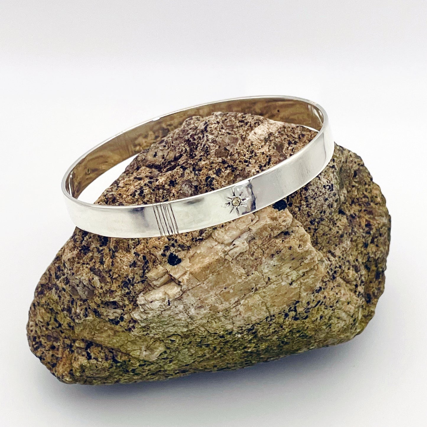 Expanded Skies Yellow Sapphire Star Set Bangle evokes the stars that shine bright in the dark skies on Dartmoor.

Three yellow Sri Lankan sapphires are star set with hand engraved rays in the signature hand-drawn aesthetic. The bangle is totally handcrafted on the edge of Dartmoor in high quality recycled sterling silver. For men and women, simple, beautiful.
