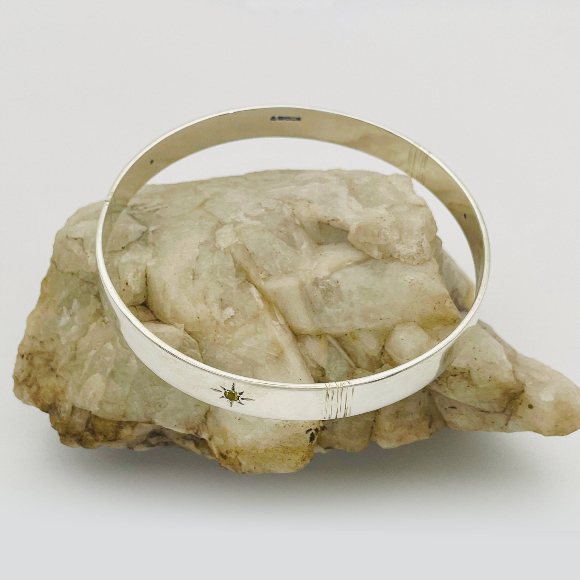Expanded Skies Yellow Sapphire Star Set Bangle evokes the stars that shine bright in the dark skies on Dartmoor.

Three yellow Sri Lankan sapphires are star set with hand engraved rays in the signature hand-drawn aesthetic. The bangle is totally handcrafted on the edge of Dartmoor in high quality recycled sterling silver. For men and women, simple, beautiful.