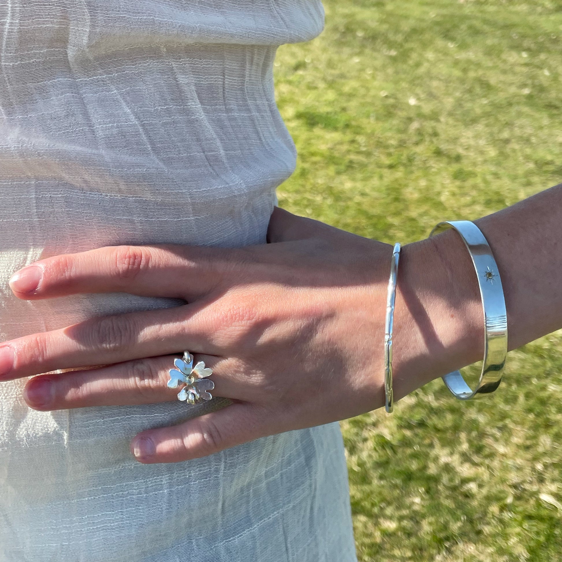 Expanded Skies Yellow Sapphire Star Set Bangle evokes the stars that shine bright in the dark skies on Dartmoor.

Three yellow Sri Lankan sapphires are star set with hand engraved rays in the signature hand-drawn aesthetic. The bangle is totally handcrafted on the edge of Dartmoor in high quality recycled sterling silver. For men and women, simple, beautiful.
The&nbsp;Expanded Skies Yellow Sapphire Star Set Bangle&nbsp;is pictured with the Expanded Skies Dartmoor Torc Bangle.