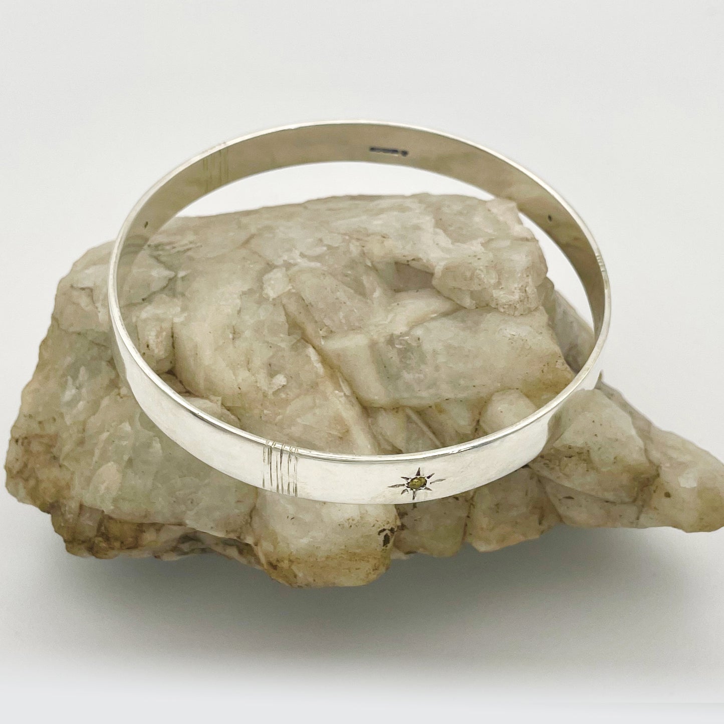 Expanded Skies Yellow Sapphire Star Set Bangle evokes the stars that shine bright in the dark skies on Dartmoor.

Three yellow Sri Lankan sapphires are star set with hand engraved rays in the signature hand-drawn aesthetic. The bangle is totally handcrafted on the edge of Dartmoor in high quality recycled sterling silver. For men and women, simple, beautiful.