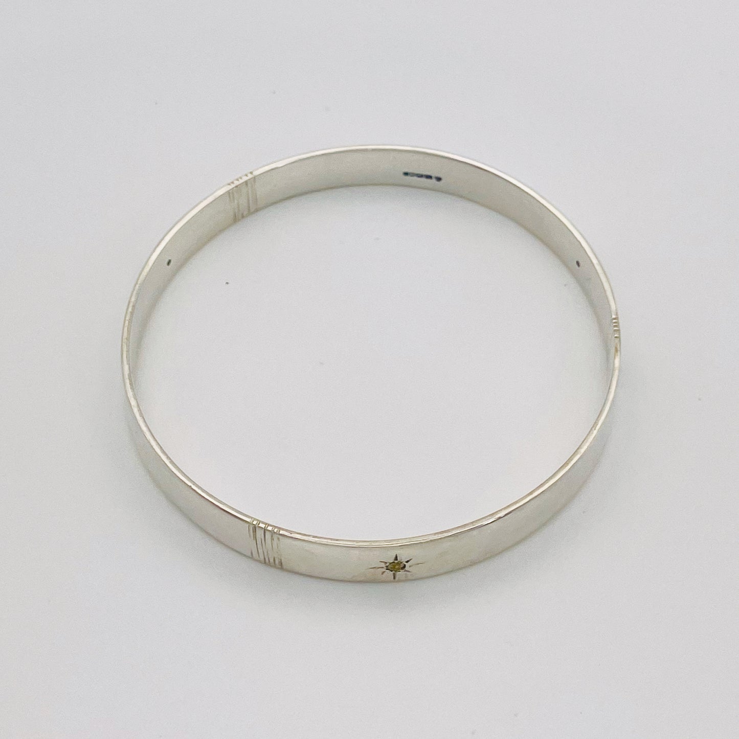 Expanded Skies Yellow Sapphire Star Set Bangle evokes the stars that shine bright in the dark skies on Dartmoor.

Three yellow Sri Lankan sapphires are star set with hand engraved rays in the signature hand-drawn aesthetic. The bangle is totally handcrafted on the edge of Dartmoor in high quality recycled sterling silver. For men and women, simple, beautiful.