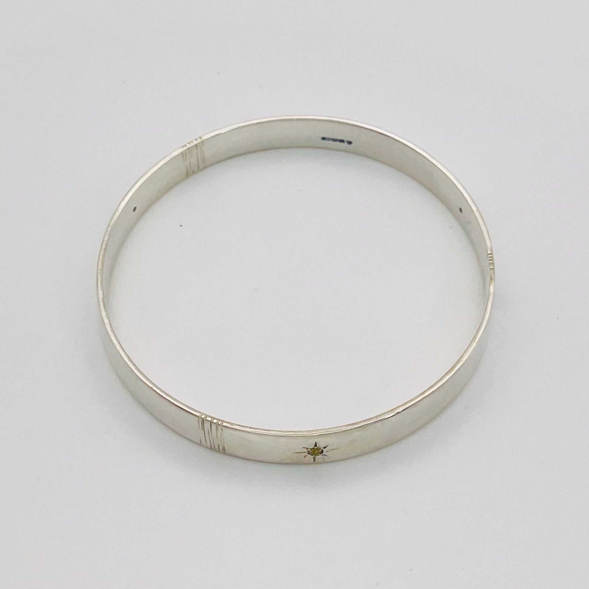 Expanded Skies Yellow Sapphire Star Set Bangle evokes the stars that shine bright in the dark skies on Dartmoor.

Three yellow Sri Lankan sapphires are star set with hand engraved rays in the signature hand-drawn aesthetic. The bangle is totally handcrafted on the edge of Dartmoor in high quality recycled sterling silver. For men and women, simple, beautiful.