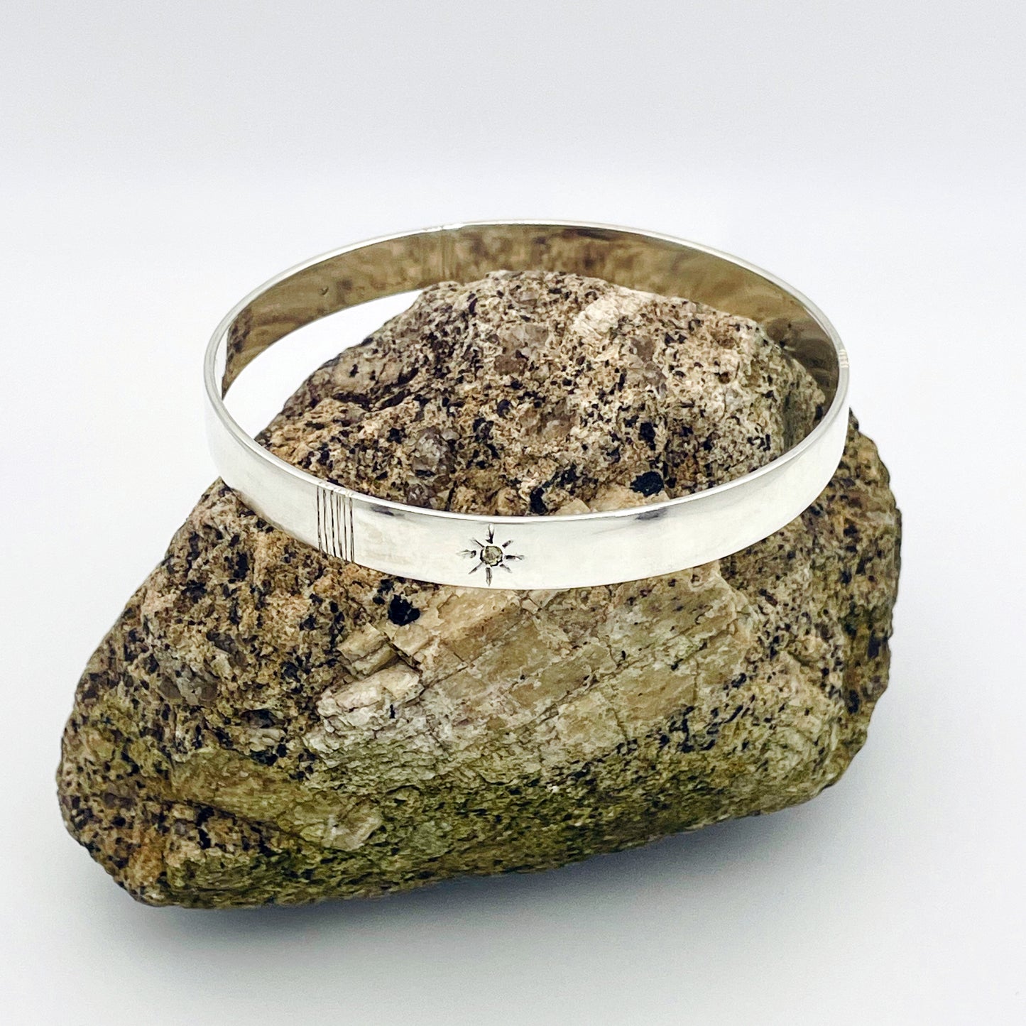 Expanded Skies Yellow Sapphire Star Set Bangle evokes the stars that shine bright in the dark skies on Dartmoor.

Three yellow Sri Lankan sapphires are star set with hand engraved rays in the signature hand-drawn aesthetic. The bangle is totally handcrafted on the edge of Dartmoor in high quality recycled sterling silver. For men and women, simple, beautiful.