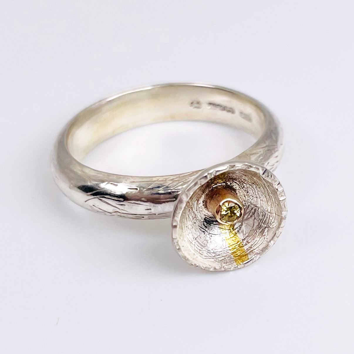 Expanded Skies Capella Star Ring is inspired by the dark Dartmoor skies and yellow Capella Star. Created with hand engraving and gold accents and a beautiful Sri Lankan, ethically sourced, yellow sapphire. Drawn with hand engraving and set with a twinkling yellow faceted sapphire in 9ct gold and fine silver.
