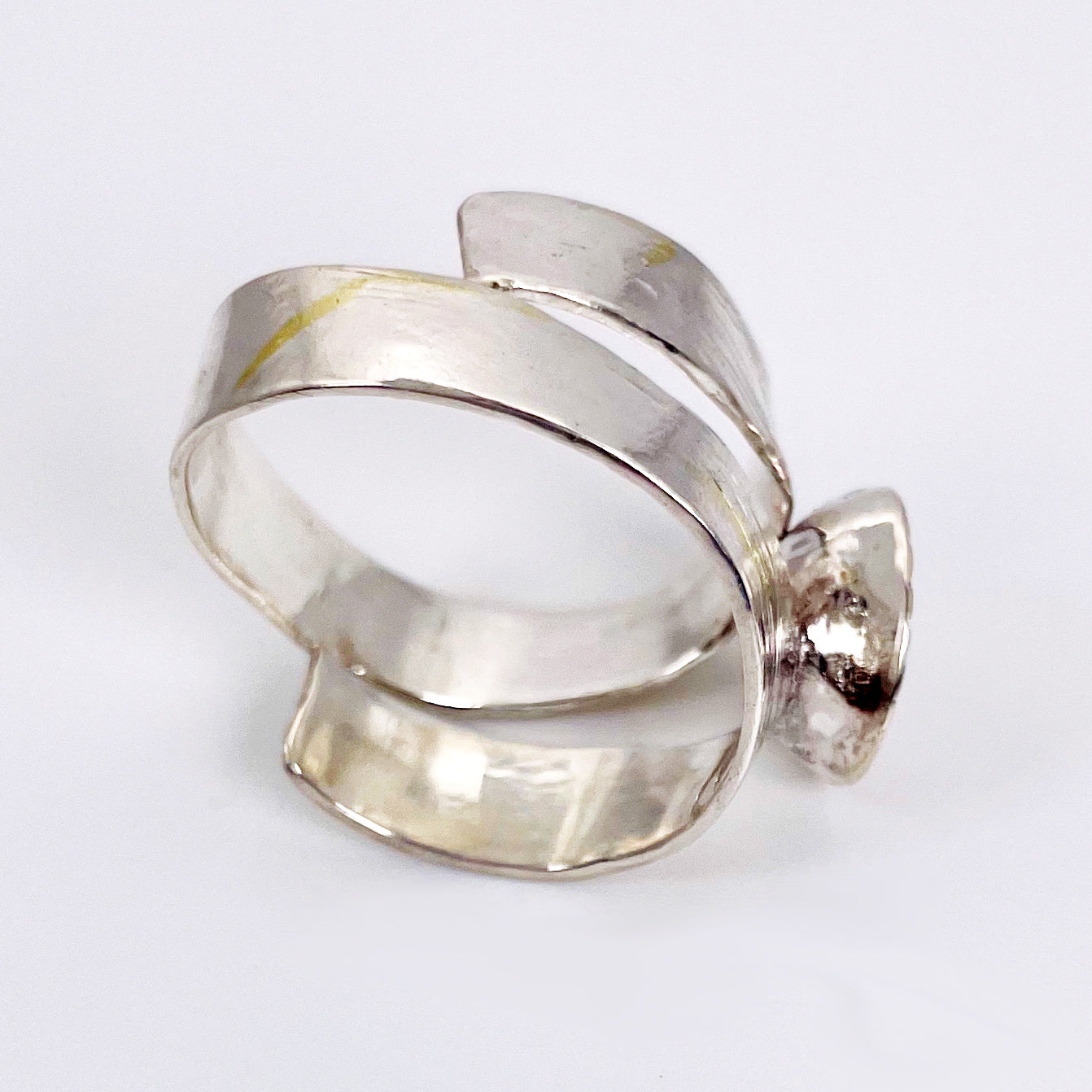 Expanded Skies River Teign Ring captures the sculptural forms of the River Teign as it moves around rocks in the Gorge, drawn with hand engraving and set with a twinkling brilliant blue sapphire in 9ct gold. The hand engraving has gold accents created by fusing 24ct gold to the silver using the kaum boo gilding process.