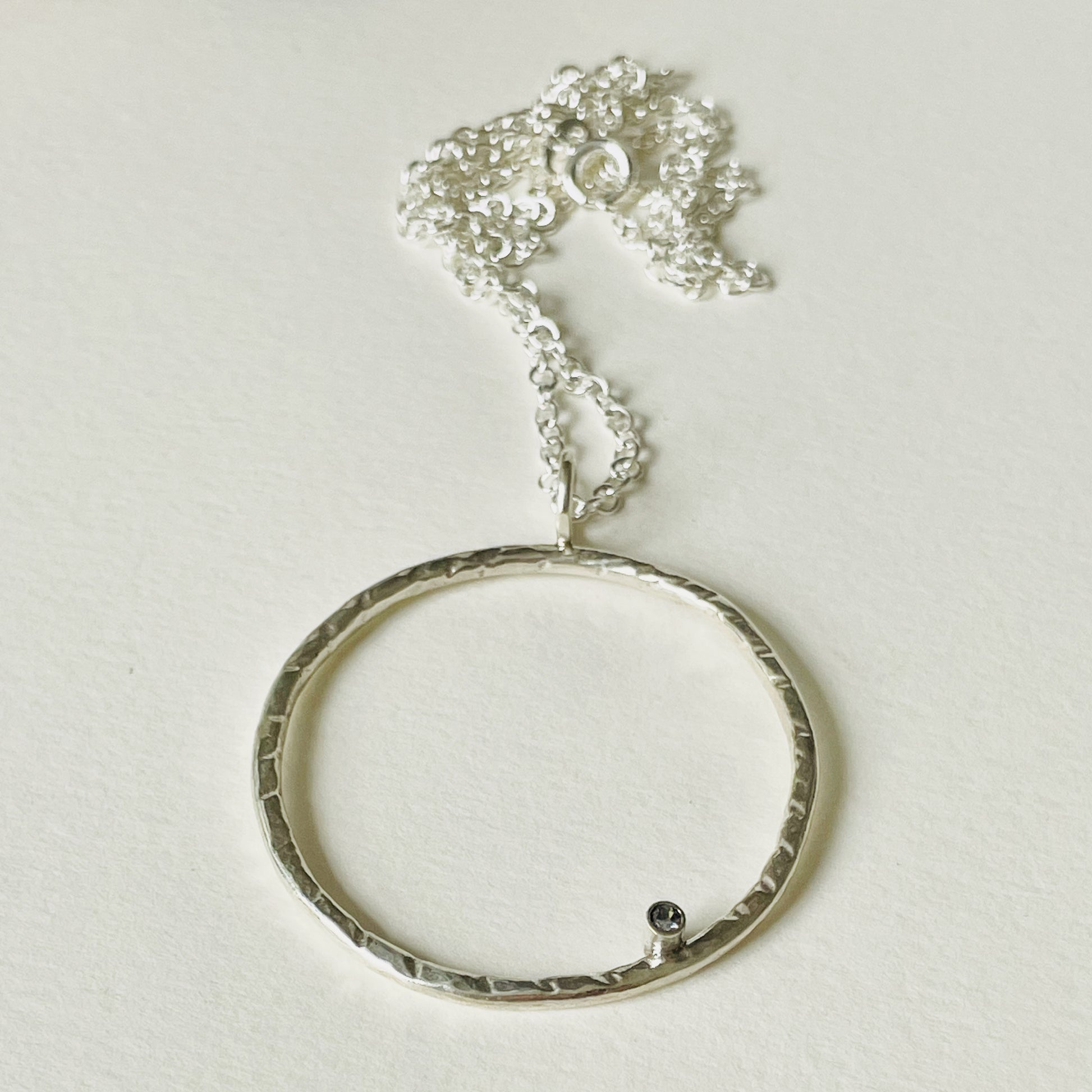 Moonbeam White Sapphire Pendant is totally handcrafted. The delicate 2mm ethically mined, Sri Lankan white sapphire is set on a hammered silver sterling silver band, made from high quality recycled sterling silver. Understated and beautiful, it can be worn everyday or for special occasions. 