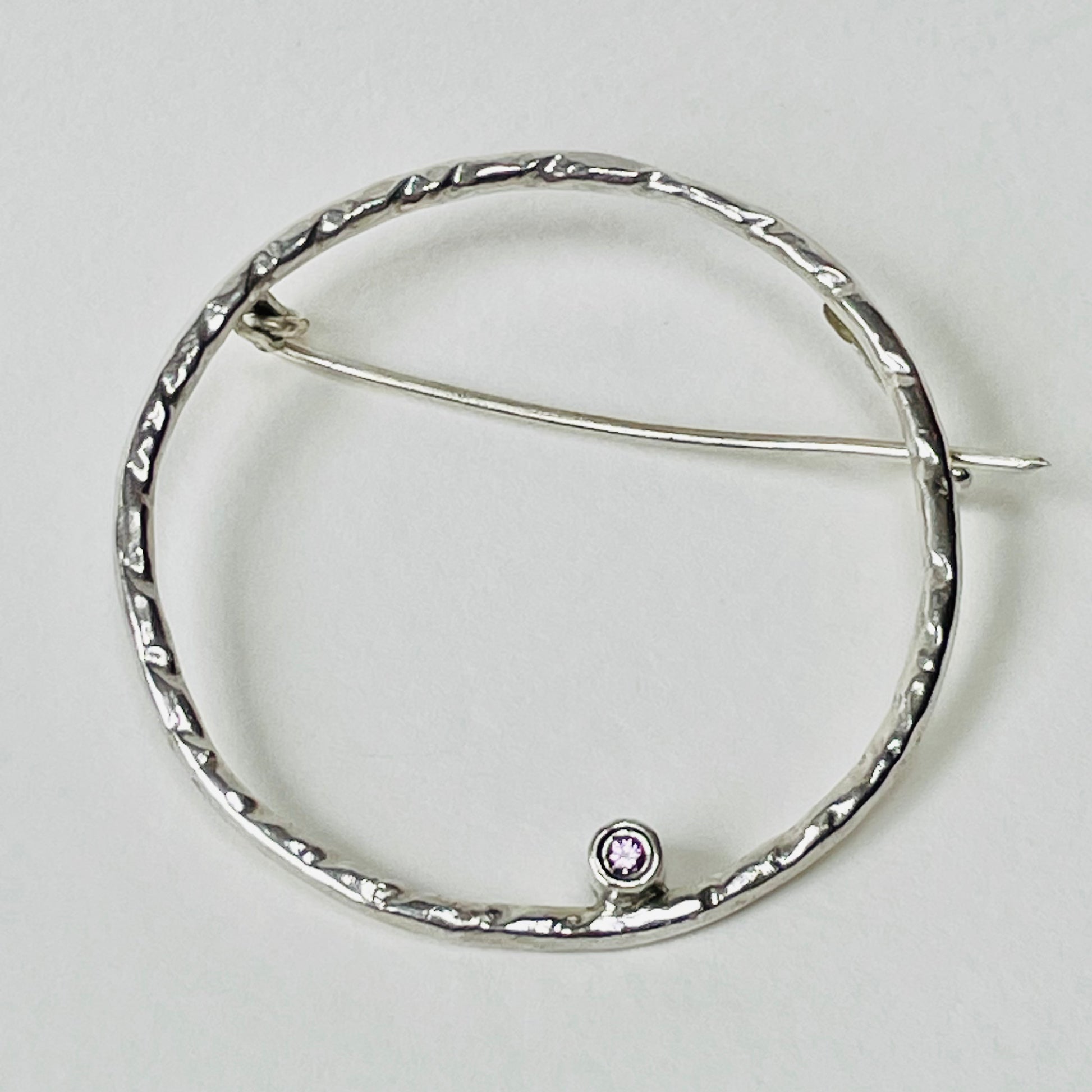 The Pink Moon Sapphire Brooch is totally handcrafted. Featuring a beautiful 2mm ethically mined pink Sri Lankan sapphire set in high quality recycled sterling silver (925) hoop.   The brooch adds a touch of glamour to casual clothes or formal wear. It can be worn as part of a set with the Full Moon White Sapphire Pendant.  Dimensions:  The brooch hoop has 35mm diameter 