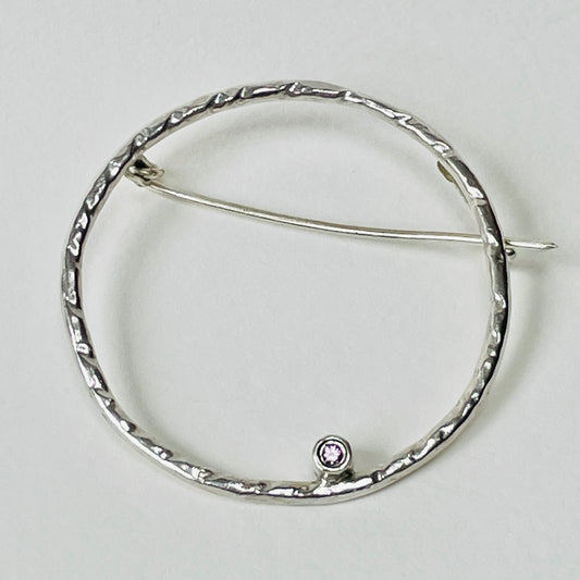 The Pink Moon Sapphire Brooch is totally handcrafted. Featuring a beautiful 2mm ethically mined pink Sri Lankan sapphire set in high quality recycled sterling silver (925) hoop.   The brooch adds a touch of glamour to casual clothes or formal wear. It can be worn as part of a set with the Full Moon White Sapphire Pendant.  Dimensions:  The brooch hoop has 35mm diameter 