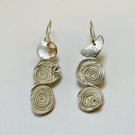 The River Dart Filigree Earrings are inspired by the River Dart that eddy around rocks, turning the flow into tiny whirlpools.
Handcrafted fine silver filigree is made with very fine silver wires are twisted to make a rope, that is sculpted and mounted onto hand engraved sterling silver. The earrings have sterling silver ear wires. Eye catching and completely unique, they are one-of-a-kind.