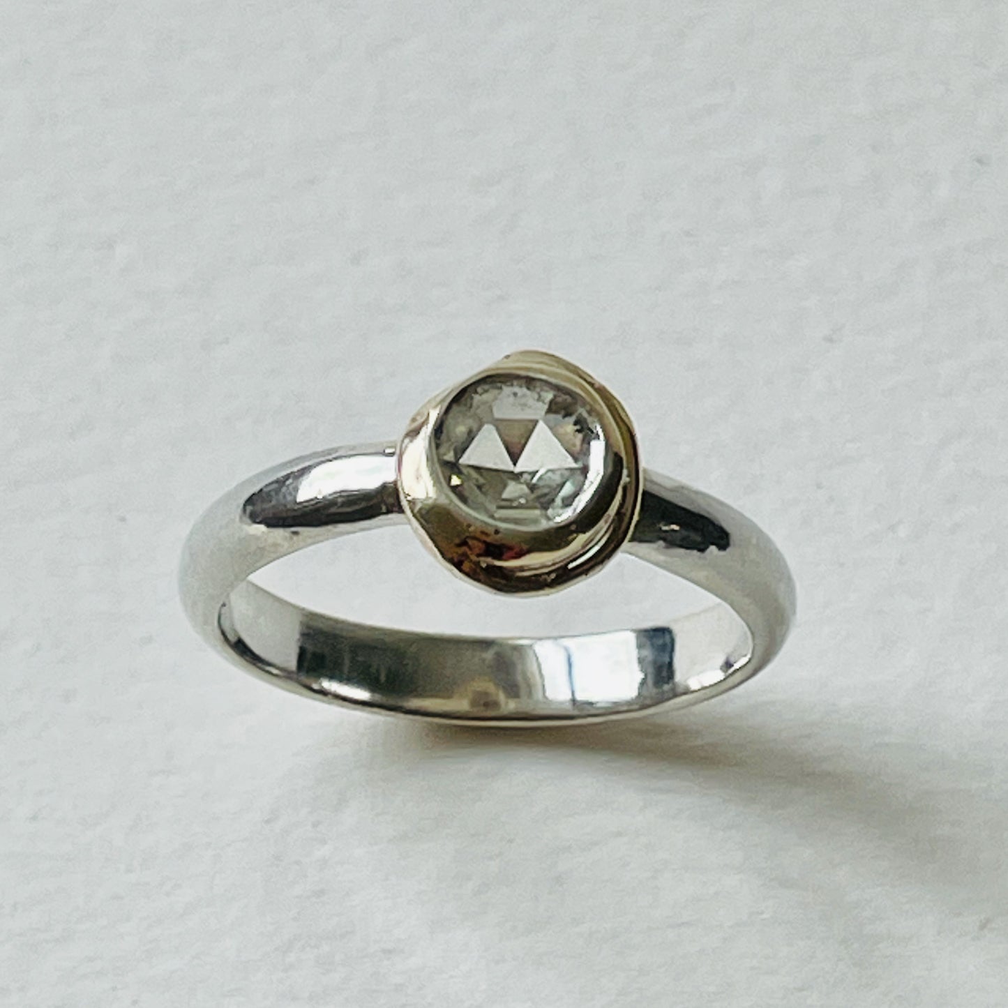 The Spiral and Pool White Sapphire Ring is inspired by Fibonacci spirals and has a beautiful ethically sourced Sri Lankan faceted white 5mm sapphire, set in 9ct gold, on sterling silver band. Completely handcrafted from high quality recycled sterling silver and recycled gold. Understated and beautiful, it can be worn every day and for special occasions.